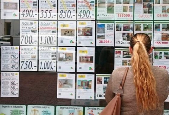 En kvinna studerar bostäder för uthyrning och till försäljning i ett fastighetsmäklarfönster på Gran Canaria