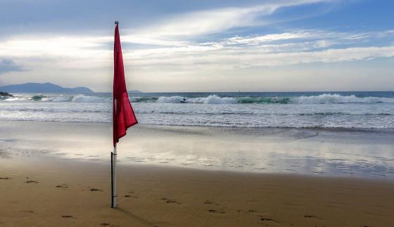 Rødt flagg på strand farevarsel