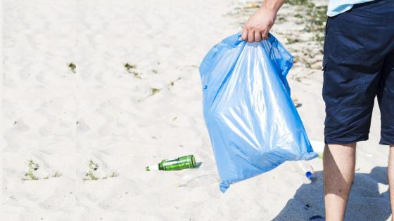 Mann bærer søppel på stranda