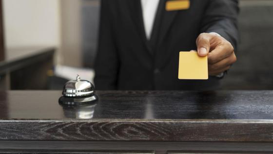 Resepsjonist leverer nøkkelkort til hotellgjest.