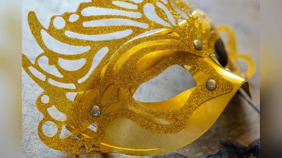 Karnevalsmaske i gull som ligger på en flate.