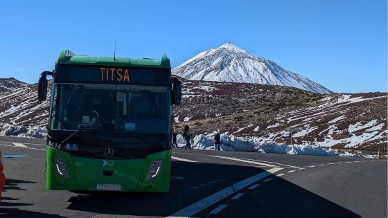 Buss på vei med snøkledt fjell i bakgrunnen.
