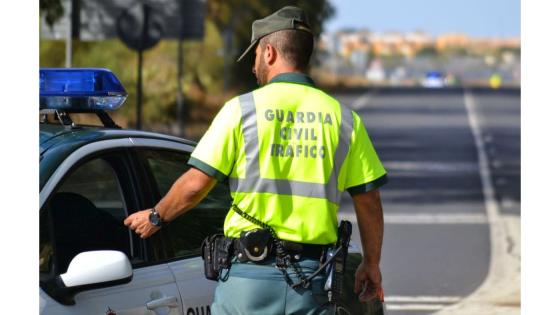 Trafikkbetjent fra Guardia Civil ved siden av en politibil.