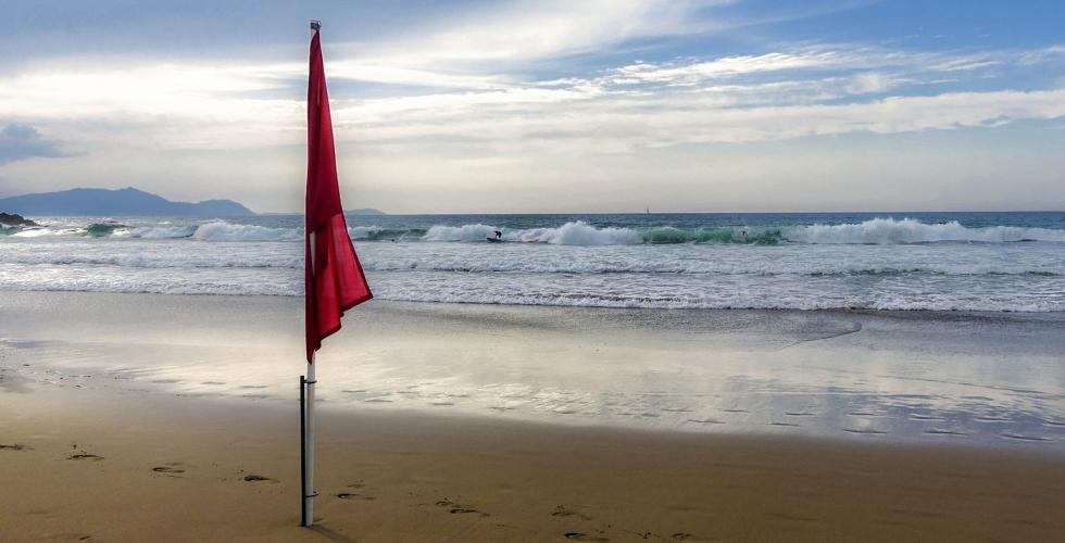 Rødt flagg på strand farevarsel