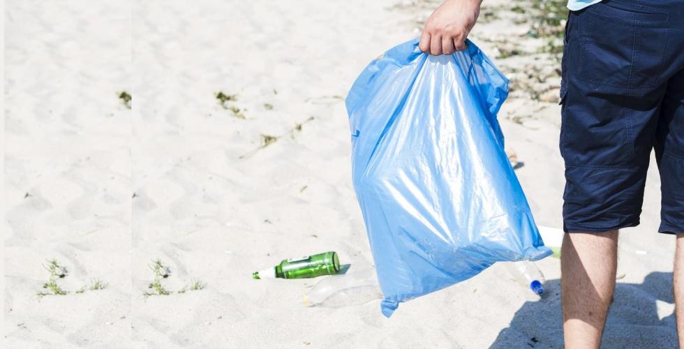 Mann bærer søppel på stranda