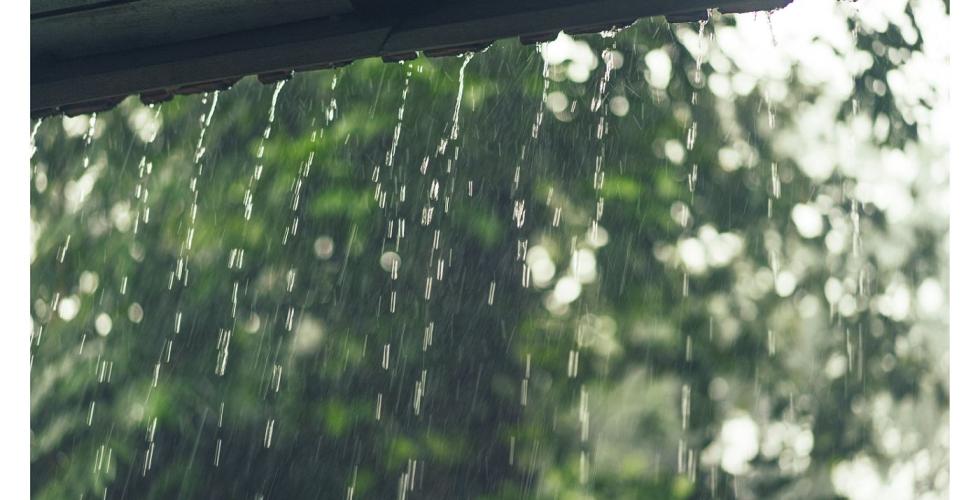 Regn sett mot tak fra vindu.