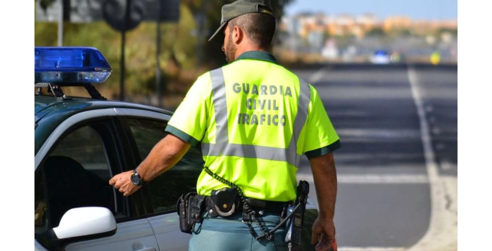 Trafikkbetjent fra Guardia Civil ved siden av en politibil.